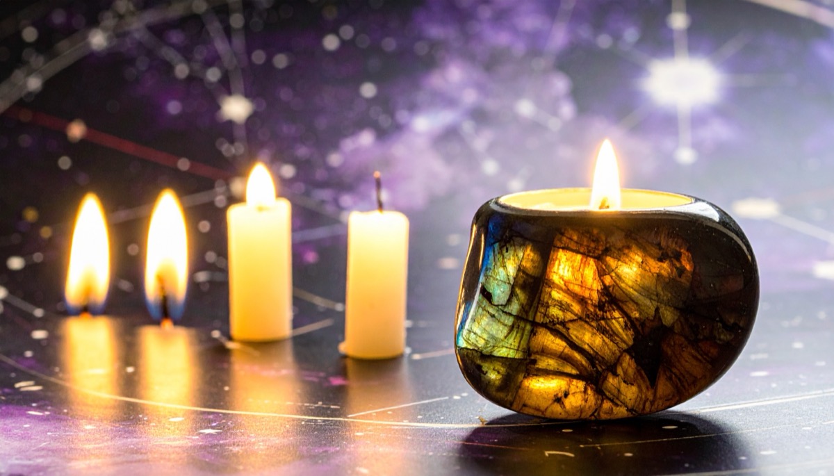 a dark polished candle holder flashing gold and blue beside four white candles on a star chart