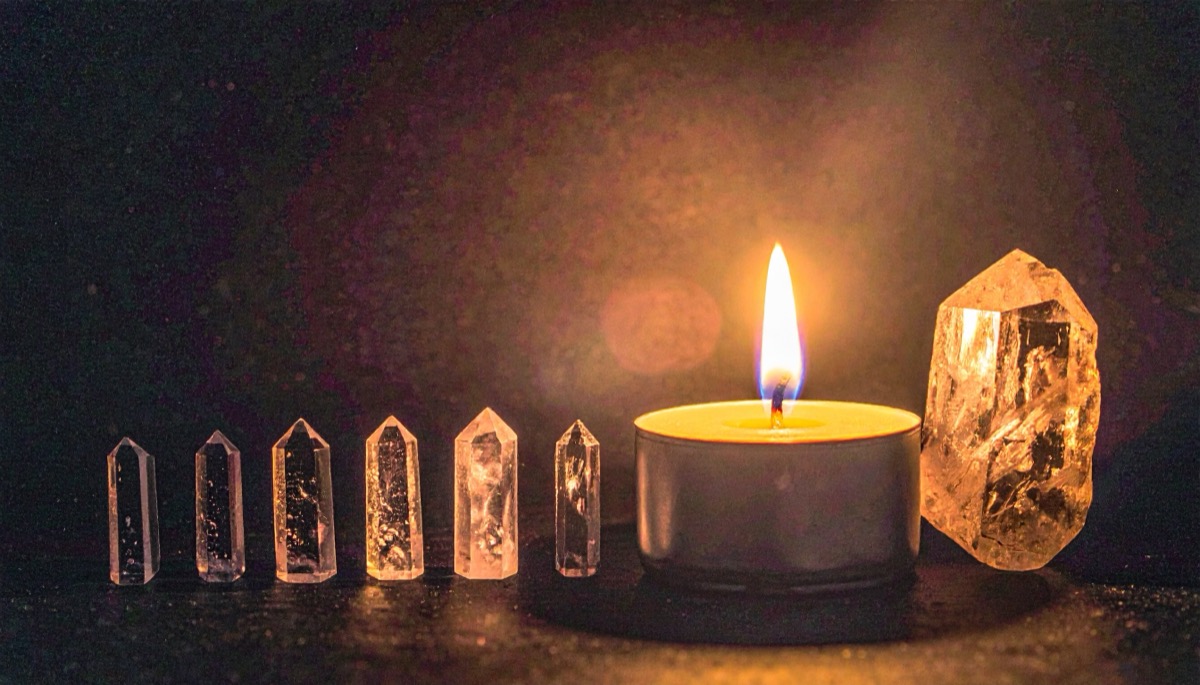 six small clear points lined up beside a lit tea light and a rough pale chunk