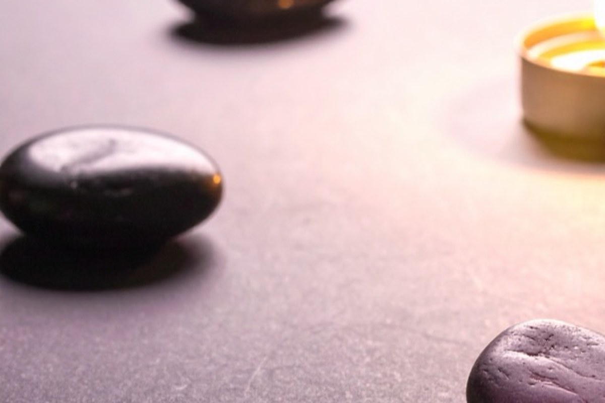 smooth dark grey pebbles laid in a wide circle around one lit tea light