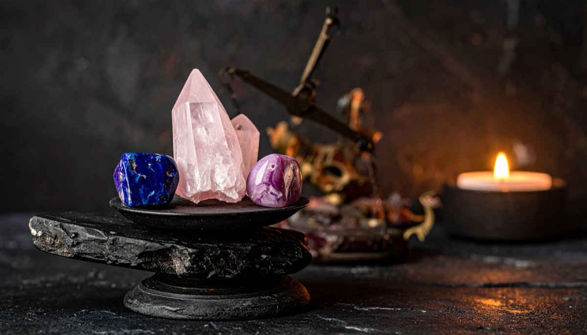 a pale pink point flanked by a blue and a pink tumbled stone balanced on a stone plinth