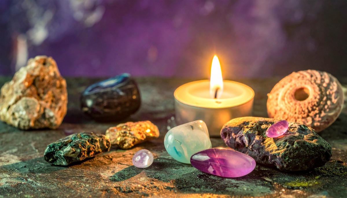 pale green, milky and violet tumbled stones with rough chunks around a lit tea light