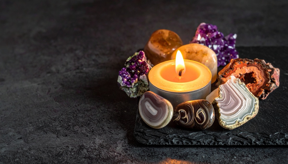 banded cream and brown slices, purple clusters and honey tumbled stones around a lit tea light