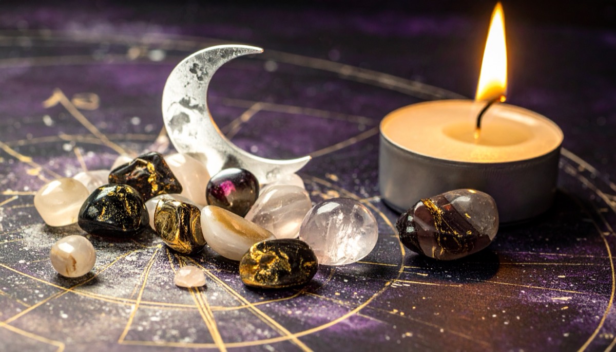 a carved crescent moon of pale stone with dark and gold tumbled stones on a star chart