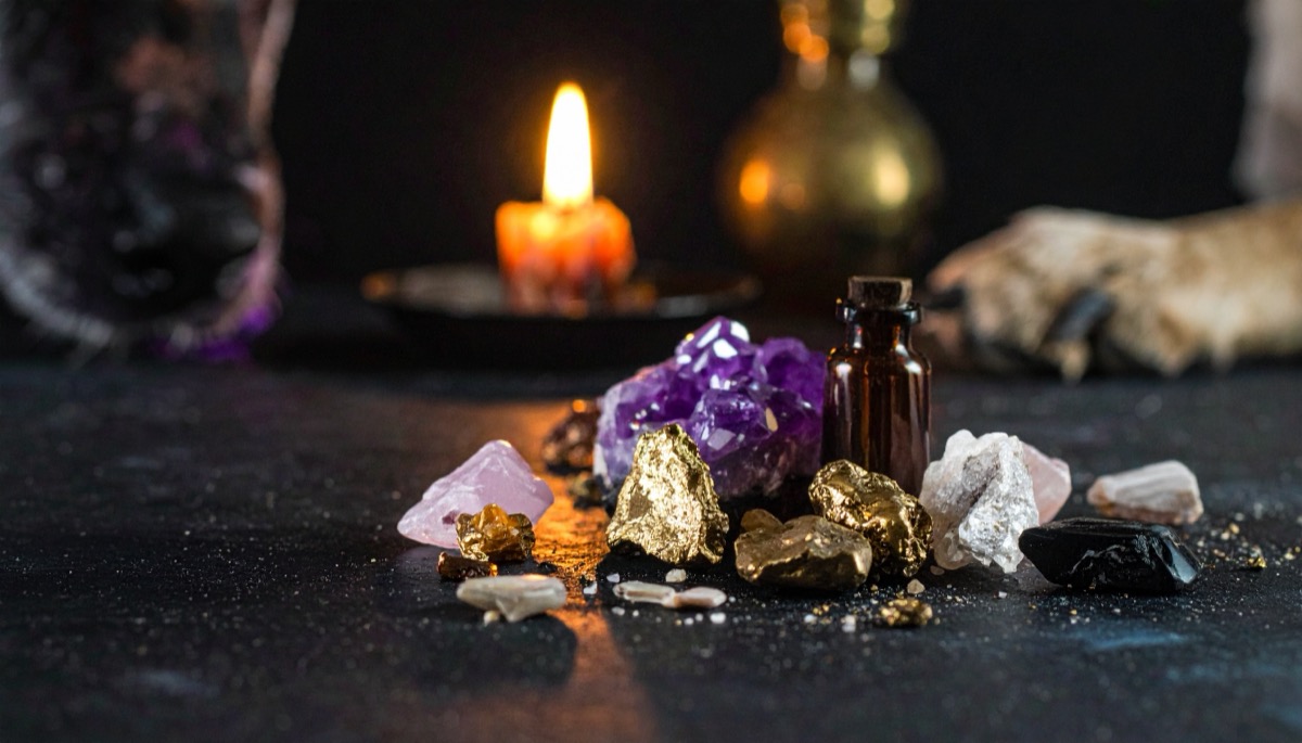 gold nuggets, a purple cluster and pale rough stones beside a small brown bottle