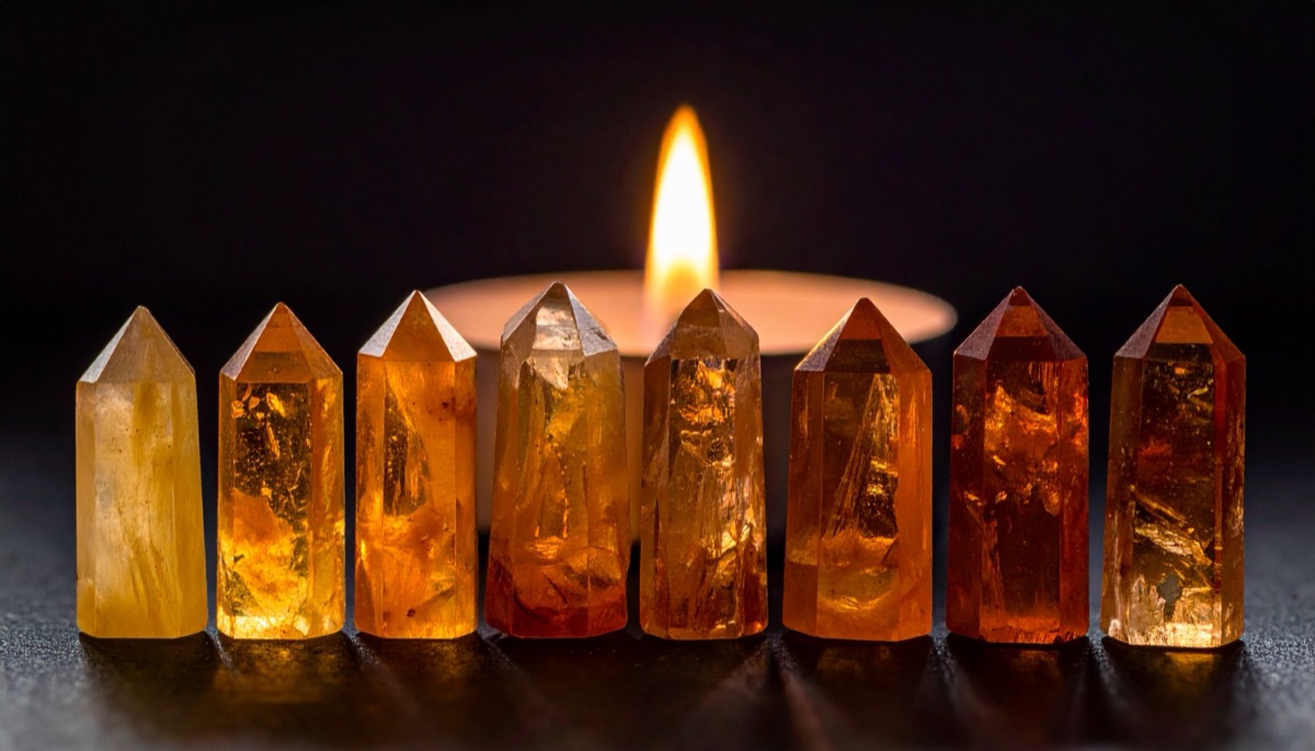 eight polished points in graded yellow to deep orange lined up before a candle flame