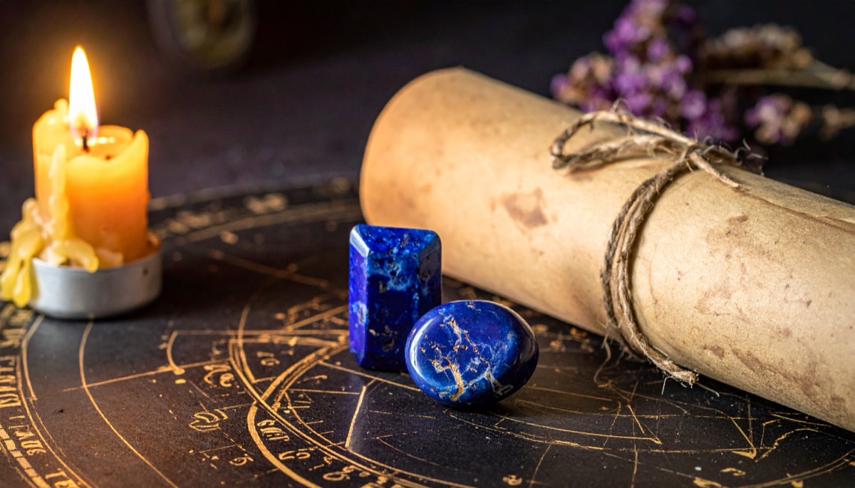 two deep blue polished stones flecked with gold on a zodiac wheel beside a tied scroll